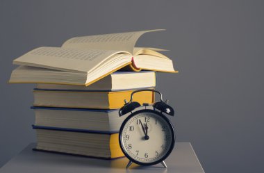 yığın kitap ve çalar saat.