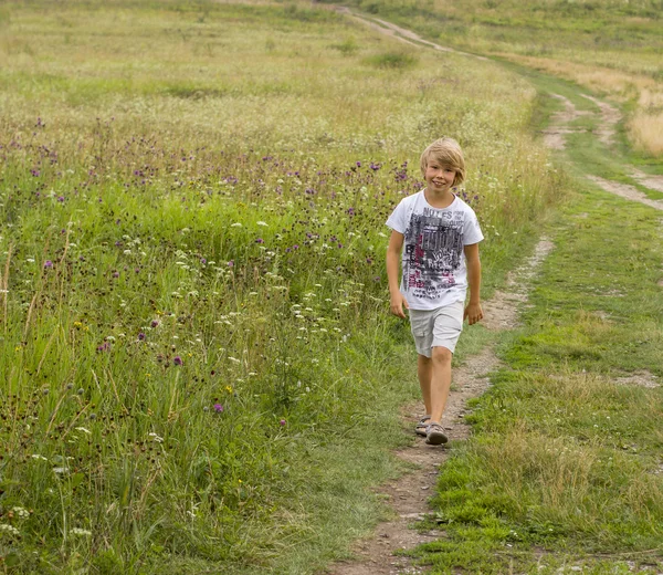 Petit garçon marchant sur le champ d'été . — Photo