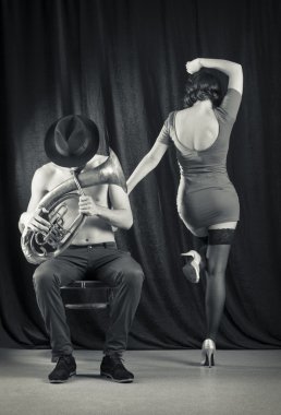 Man playing the trumpet, and a woman dancing.