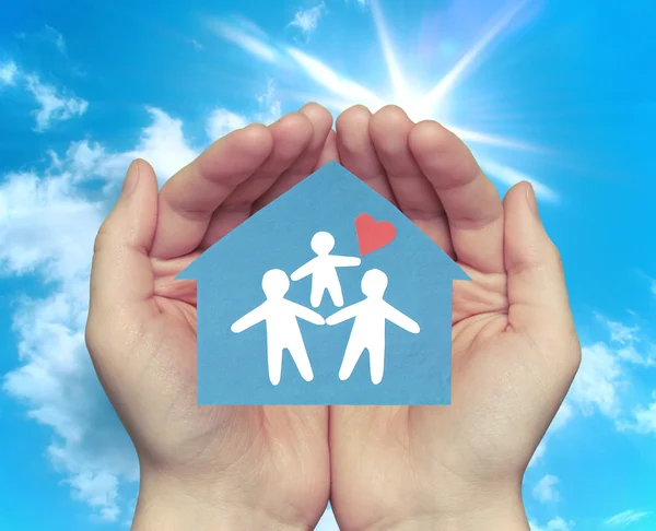 Hands holding house with happy family — Stock Photo, Image