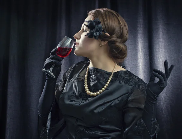 Vrouw in een retro-stijl met een glas rode wijn. Stockfoto