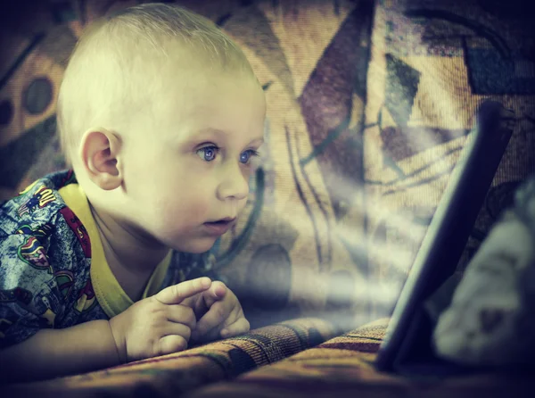 Baby boy looks at a computer screen. — Stock Photo, Image