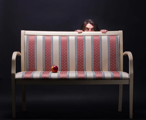 Homem escondido atrás de um sofá retro — Fotografia de Stock
