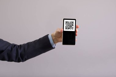 Akıllı telefon ekranında QR kodu var, bu da bir adamın elinde. Soru-cevap kodu ile onaylanan kişinin zorunlu aşılanması kavramı.