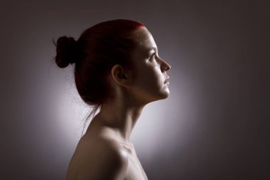 Karanlık bir arka planda profilde güzel bir genç kadının portresi..