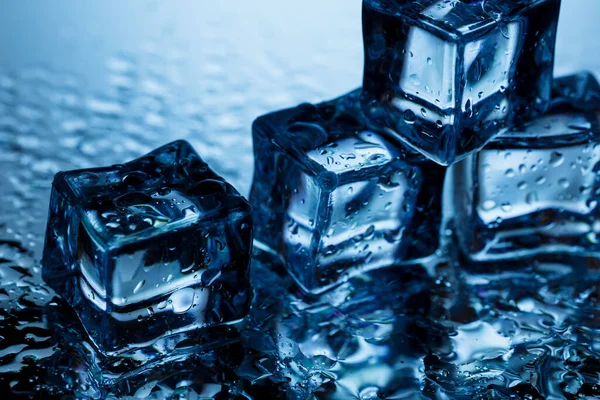 青い背景に氷のキューブと水がクローズアップされます ストック画像