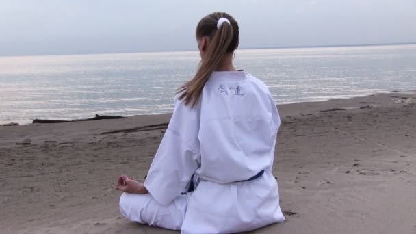 Jonge vrouw meditatie op zonsondergang strand — Stockvideo