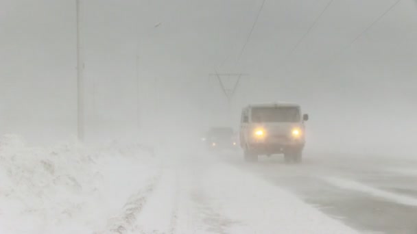 Автомобілі їдуть по дорозі в сніжну бурю — стокове відео