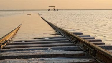 Tuz gölünün içinden geçen eski tren raylarda yüzer. Tren sudan gelir. Burlin Gölü 'nde tuz madeni. Altai. Bursol. - Rusya. Ağustos 2019
