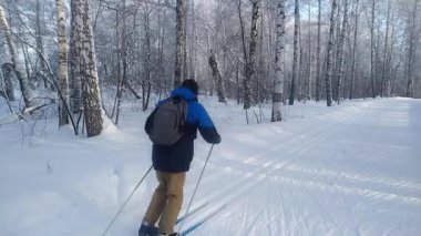 Adam kış günü karlı ormanda kayak yapıyor.
