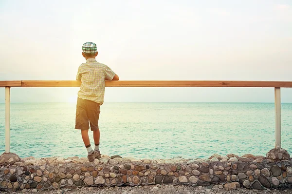 Boy standing on quay in the dusk looking at sea Stock Image