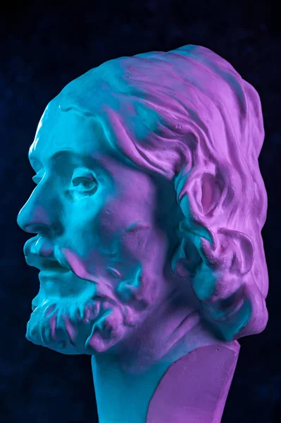 Färgglada gips kopia av antika statyn av John Döparen huvud för konstnärer på en mörk strukturerad bakgrund. Gipsskulptur man ansikte. Johannes döpte Jesus. Konstaffisch i lila och blått ljusa färger. — Stockfoto