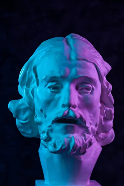 Colorful gypsum copy of ancient statue of John the Baptist head for artists on a dark textured background. Plaster sculpture man face. John baptized Jesus. Art poster in purple and blue bright colors. — Stock Photo, Image