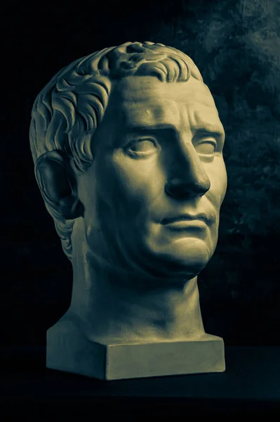 Bronzová barva sádrovec kopie starověké sochy Guy Julius Caesar Octavian Augustus hlavu pro umělce na tmavém texturovaném pozadí. Renesanční epocha. Sádrová plastika mužského obličeje.Šablona pro výtvarný design — Stock fotografie