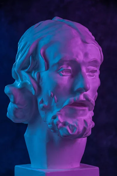 Färgglada gips kopia av antika statyn av John Döparen huvud för konstnärer på en mörk strukturerad bakgrund. Gipsskulptur man ansikte. Johannes döpte Jesus. Konstaffisch i lila och blått ljusa färger. — Stockfoto