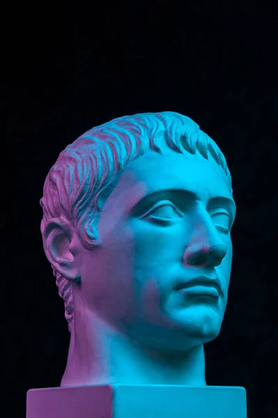 Blauw paars gips kopie van oud standbeeld van Germanicus Julius Caesar hoofd voor kunstenaars geïsoleerd op zwarte achtergrond. Renaissance tijdperk. Pleistersculptuur van het gezicht van een man. Model voor kunstontwerp Stockfoto