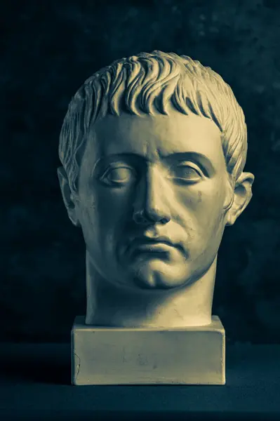 Bronzefarbene Gipskopie einer antiken Statue des Germanikus Julius Caesar für Künstler auf schwarzem Hintergrund. Epoche der Renaissance. Gipsskulptur des menschlichen Gesichts. Vorlage für Kunstdesign Stockbild