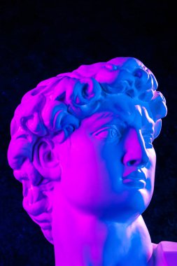 Michelangelo 'dan David' in ünlü heykelini görün. Karanlık arka plandaki sanatçılar için parlak neon renkli baş heykelinin alçıtaşı kopyası. DJ, moda, poster, zine, kolaj için şablon tasarımı.