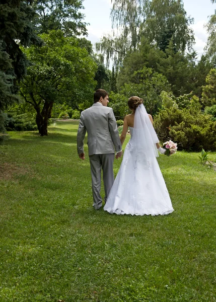 Bride and groom walking in a park — Stock Photo, Image
