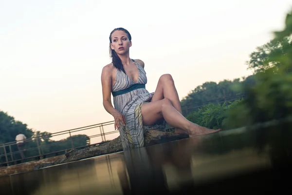 Pretty girl in cotton dress is sitting on the log — Stock Photo, Image