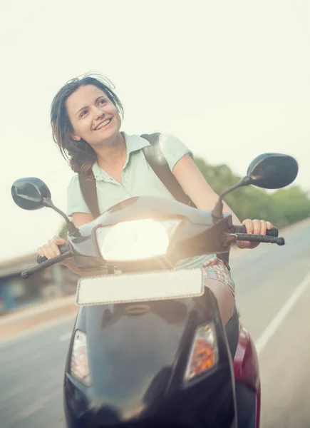 Pretty smiling woman is riding a scooter — Stock Photo, Image