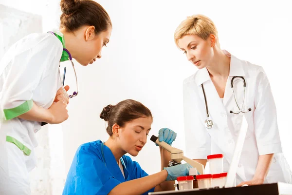 Doctors and assistant working with microscope — Stock Photo, Image
