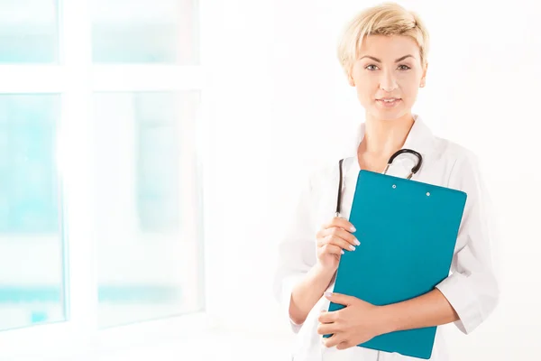 Junge Ärztin im weißen Kittel mit grüner Tablette lizenzfreie Stockbilder