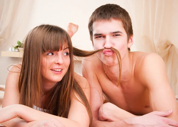 Gelukkige jonge paar. Boy is het maken van een snor van haar haren — Stockfoto