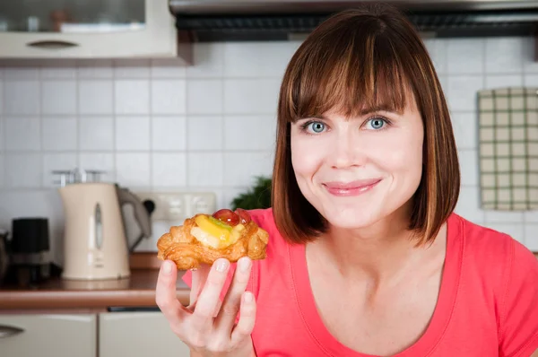 Beautiful woman holds sweet bun with fruits — Stock Photo, Image