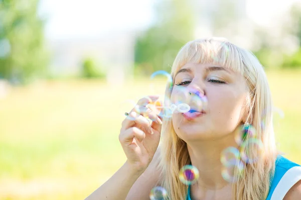 Kvinna blåser bubblor i park — Stockfoto