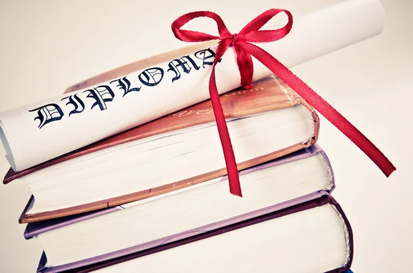 Diploma met rood lint en boeken — Stockfoto