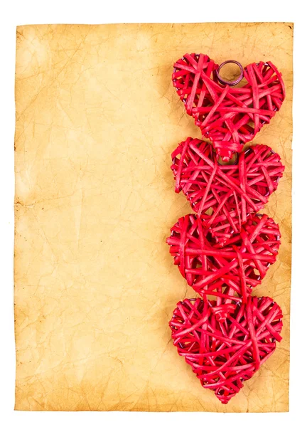 Red straw hearts on old paper — Stock Photo, Image