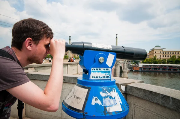 The man looks through telescope in Prague