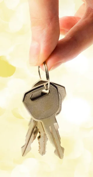 Human hand with keys on holiday lights — Stock Photo, Image