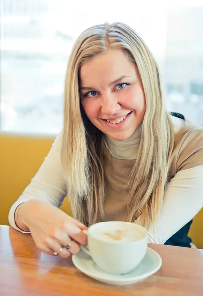 Lächelnde junge Frau trinkt Kaffee aus einer weißen Tasse — Stockfoto