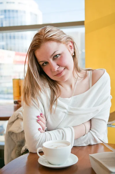 Eine junge Frau sitzt an einem Tisch im Café. trinkt Kaffee — Stockfoto