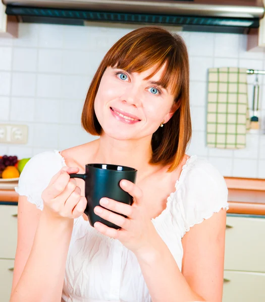 Ung kvinna, njuter av en kopp kaffe i hennes hem. — Stockfoto