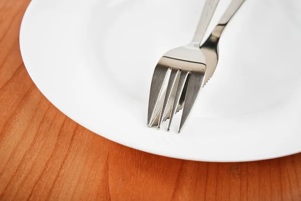 Нож и вилка на белой тарелке — стоковое фото