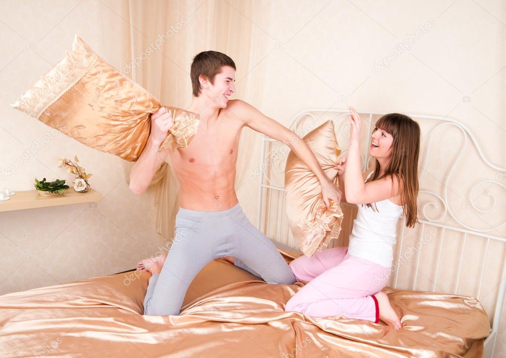 Young couple fighting pillows in the bedroom