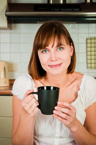 Junge Frau genießt eine Tasse Kaffee in ihrem Haus. — Stockfoto