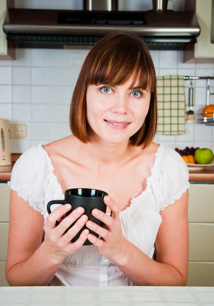 Молода жінка, насолоджуючись чашкою кави в її будинку . — стокове фото
