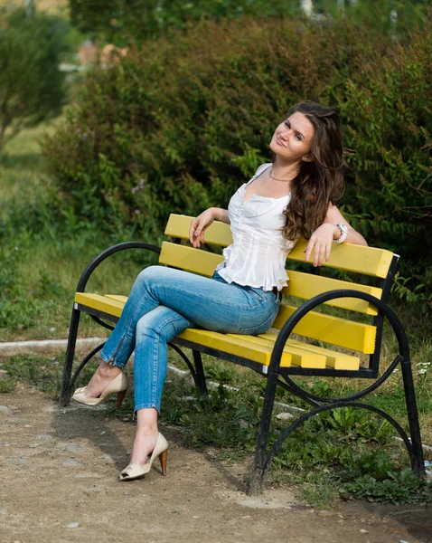 Belle femme assise sur un banc dans le parc — Photo