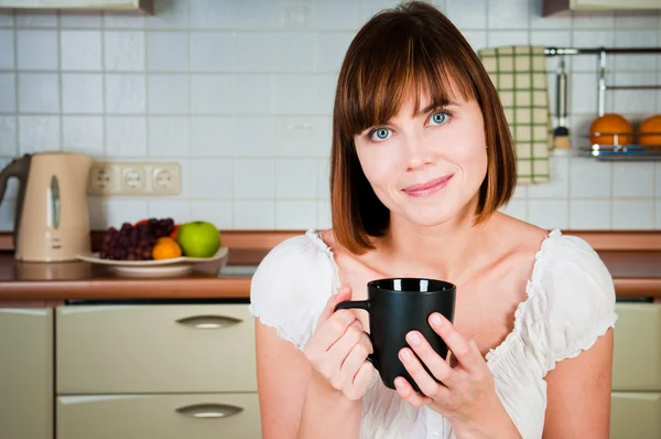 Ung kvinna, njuter av en kopp kaffe i hennes hem. — Stockfoto