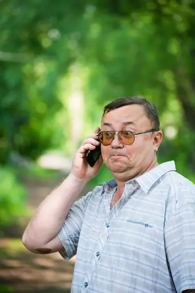 Белый мужчина с мобильным телефоном в природе — стоковое фото