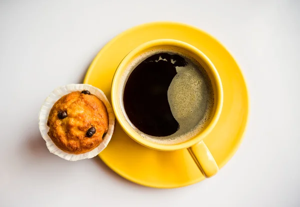 Café em uma xícara amarela e um queque — Fotografia de Stock