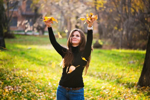 Jovem mulher jogando folhas mulher na floresta — Fotografia de Stock