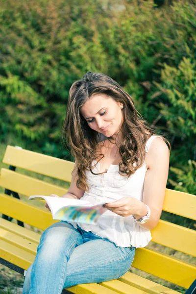 Kvinna läsa en tidning i park — Stockfoto