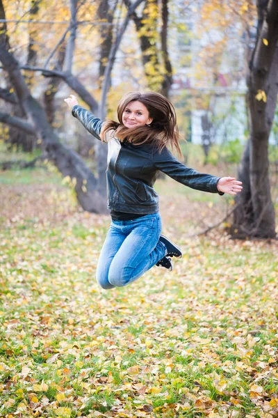 Fille dans la veste noire saute dans le parc en automne — Photo