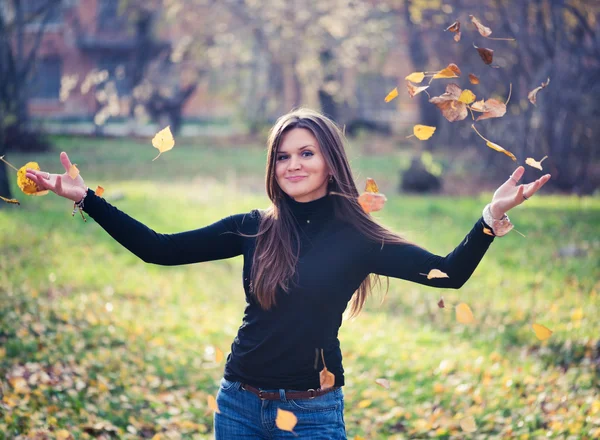 Jeune femme jetant des feuilles femme dans la forêt — Photo