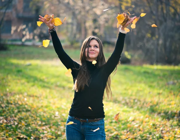 Jovem mulher jogando folhas mulher na floresta — Fotografia de Stock